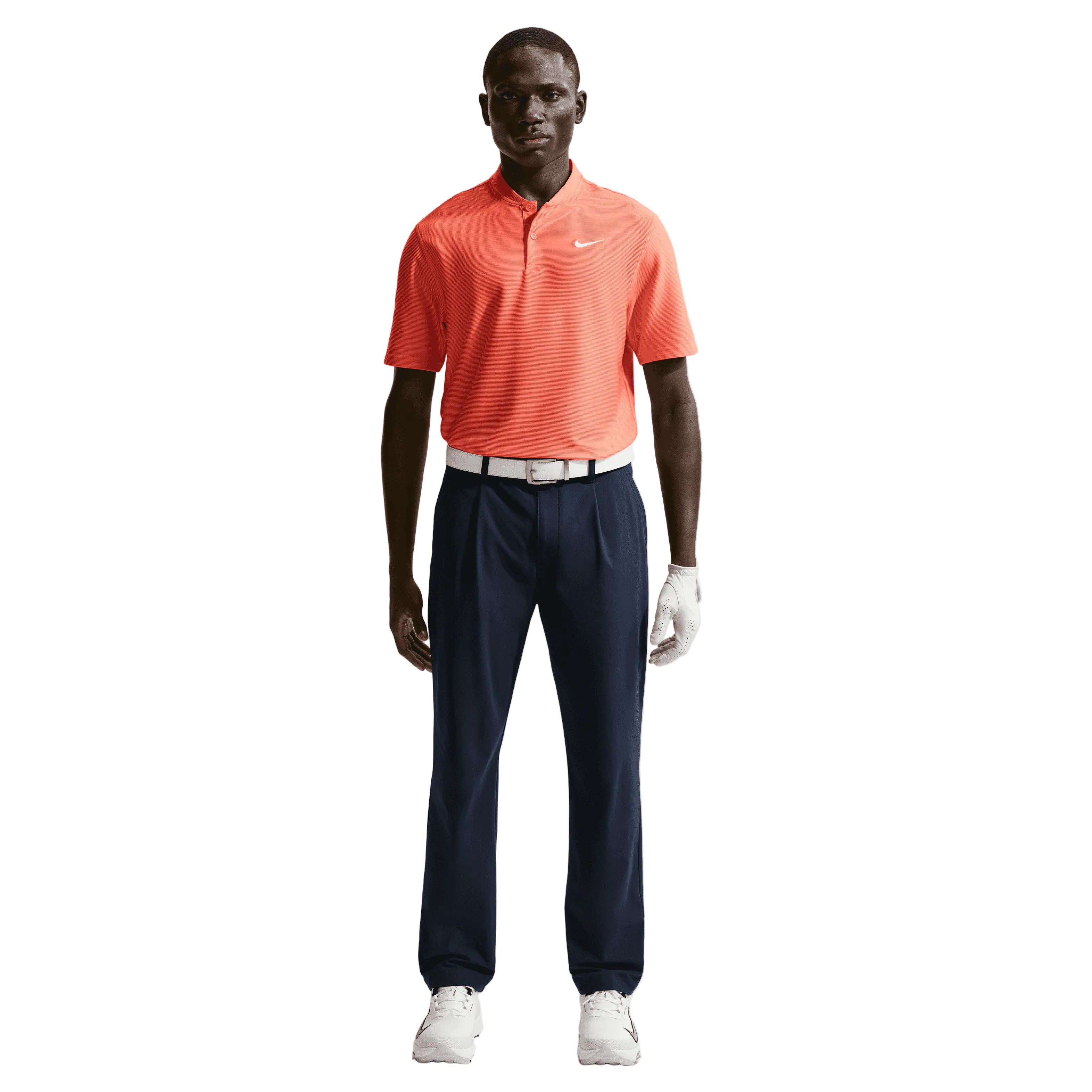 Man wearing an orange nike polo shirt, navy nike pants, and white shoes on a white background