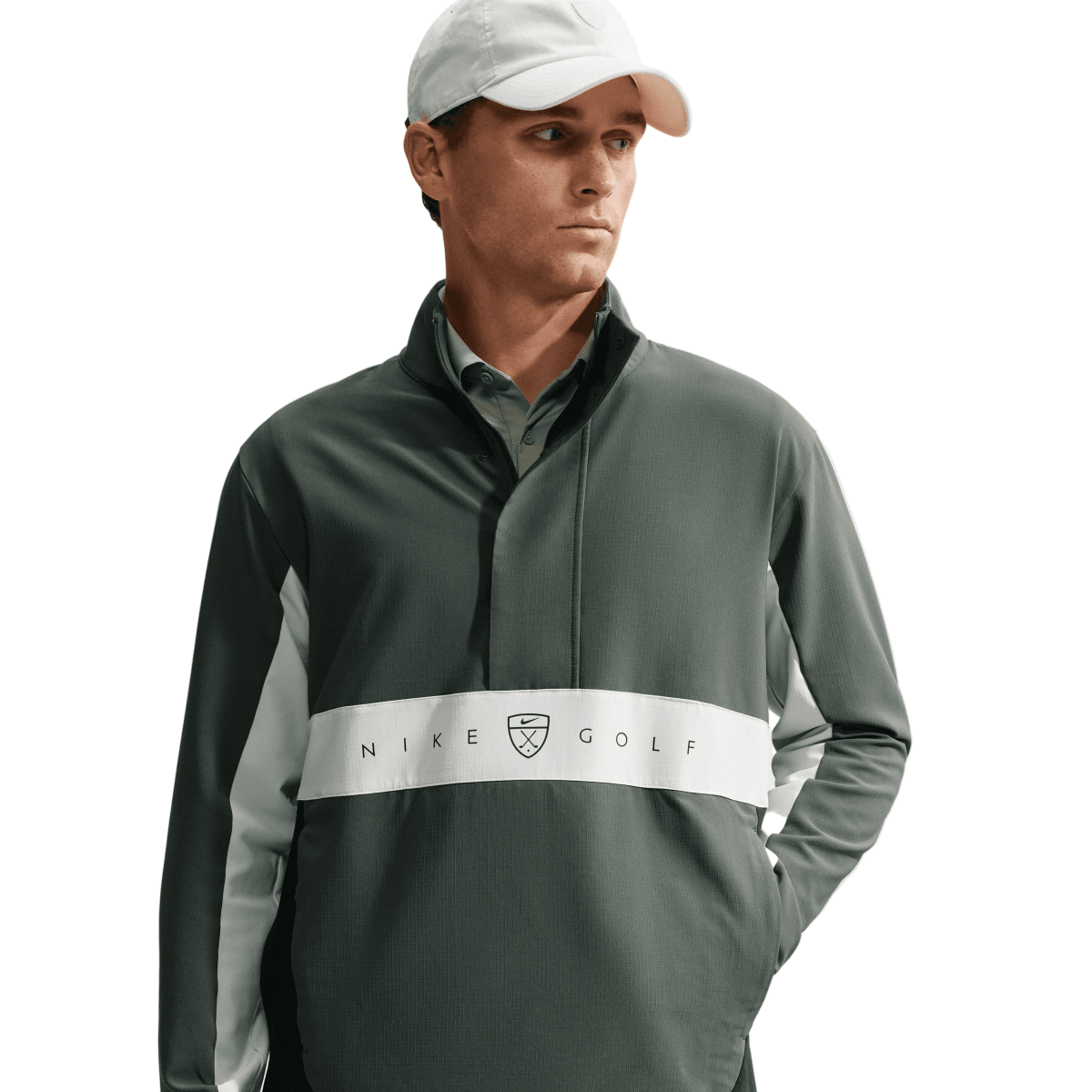A man wearing a dark green Nike Golf long-sleeve quarter-zip pullover with a white chest stripe and a white baseball cap, shown against a light gray studio background.