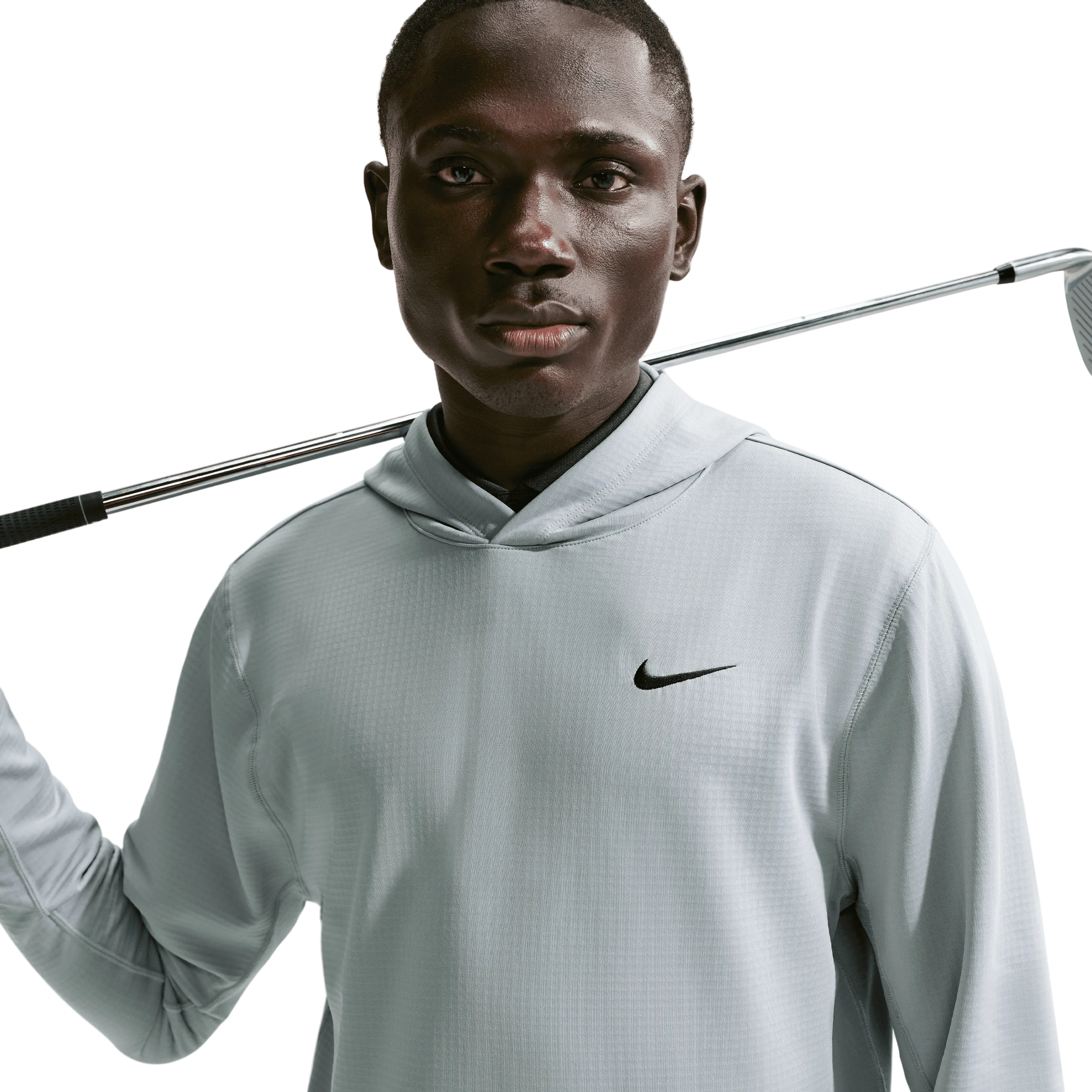 Man holding a golf club wearing a Nike shirt against a light background